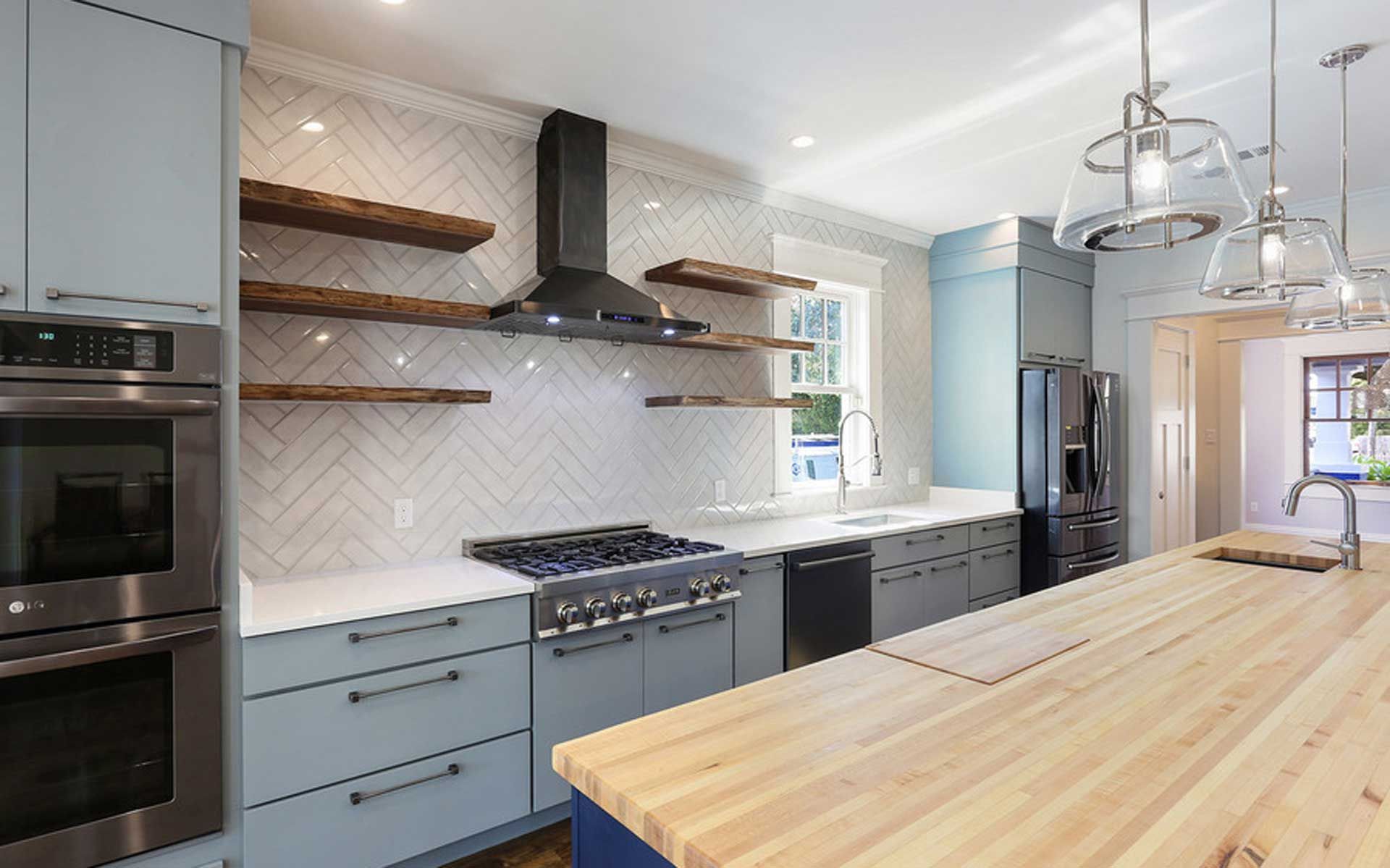 A kitchen with blue cabinets , stainless steel appliances , wooden counter tops and a large island.