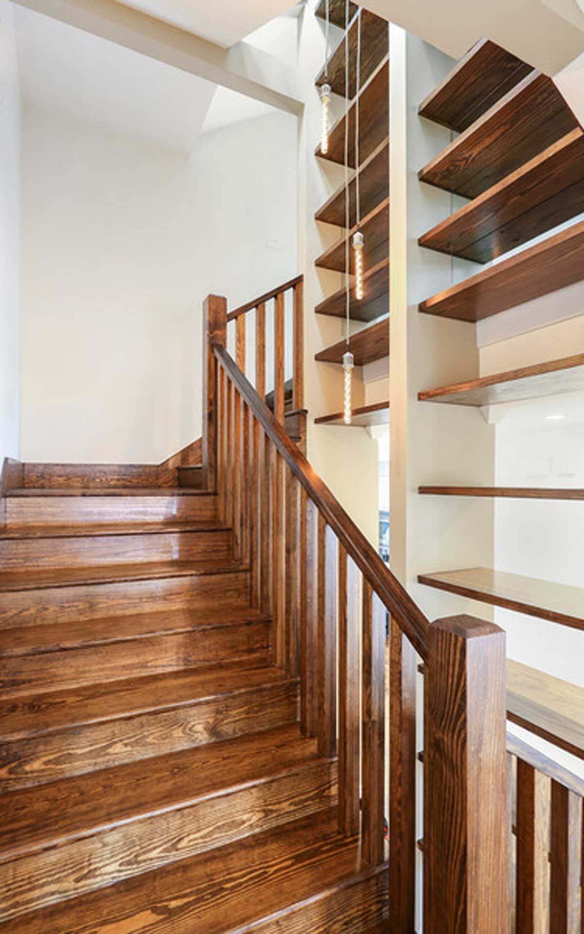 A wooden staircase with a wooden railing and shelves in a house.