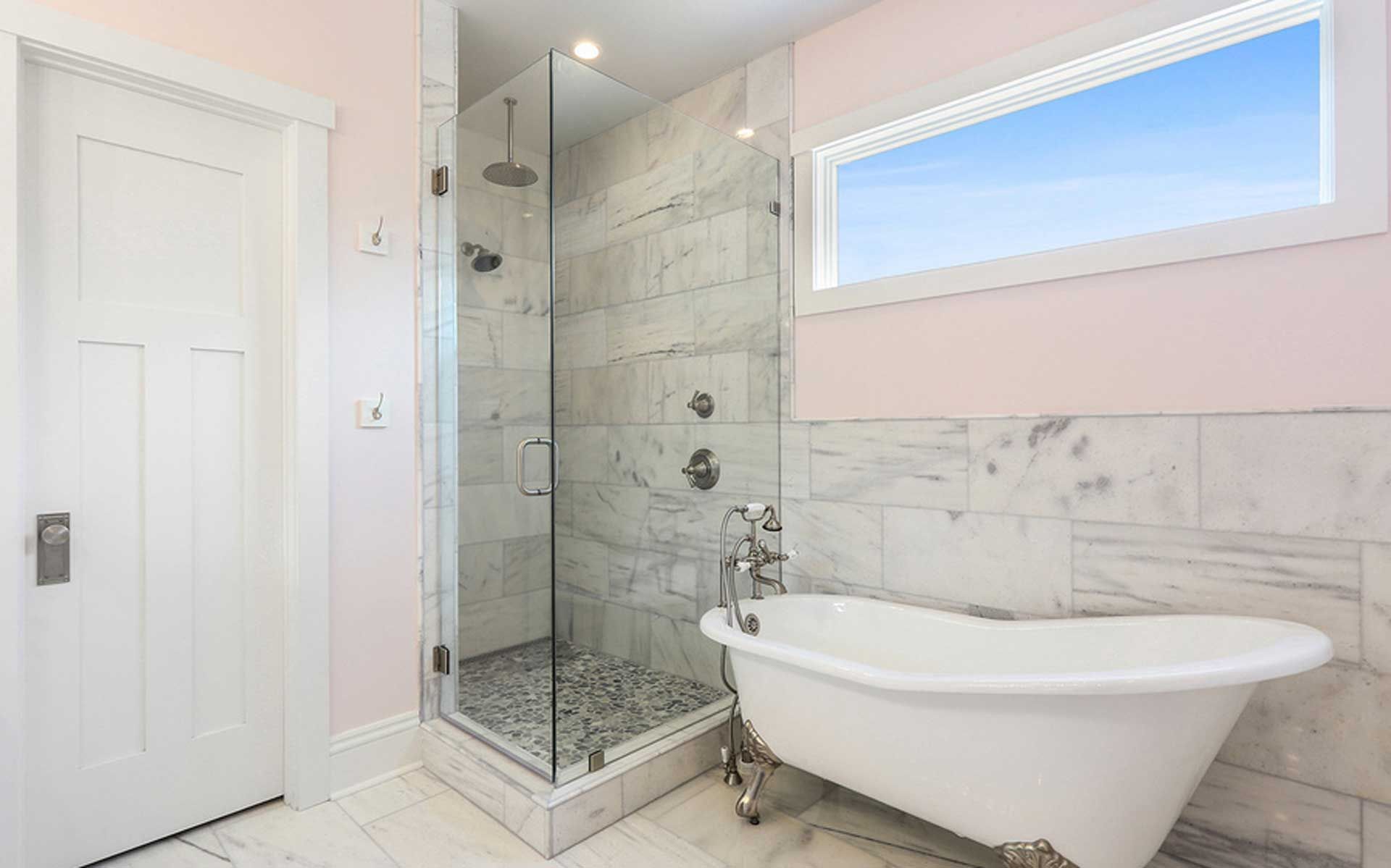 A bathroom with a tub , shower , and window.