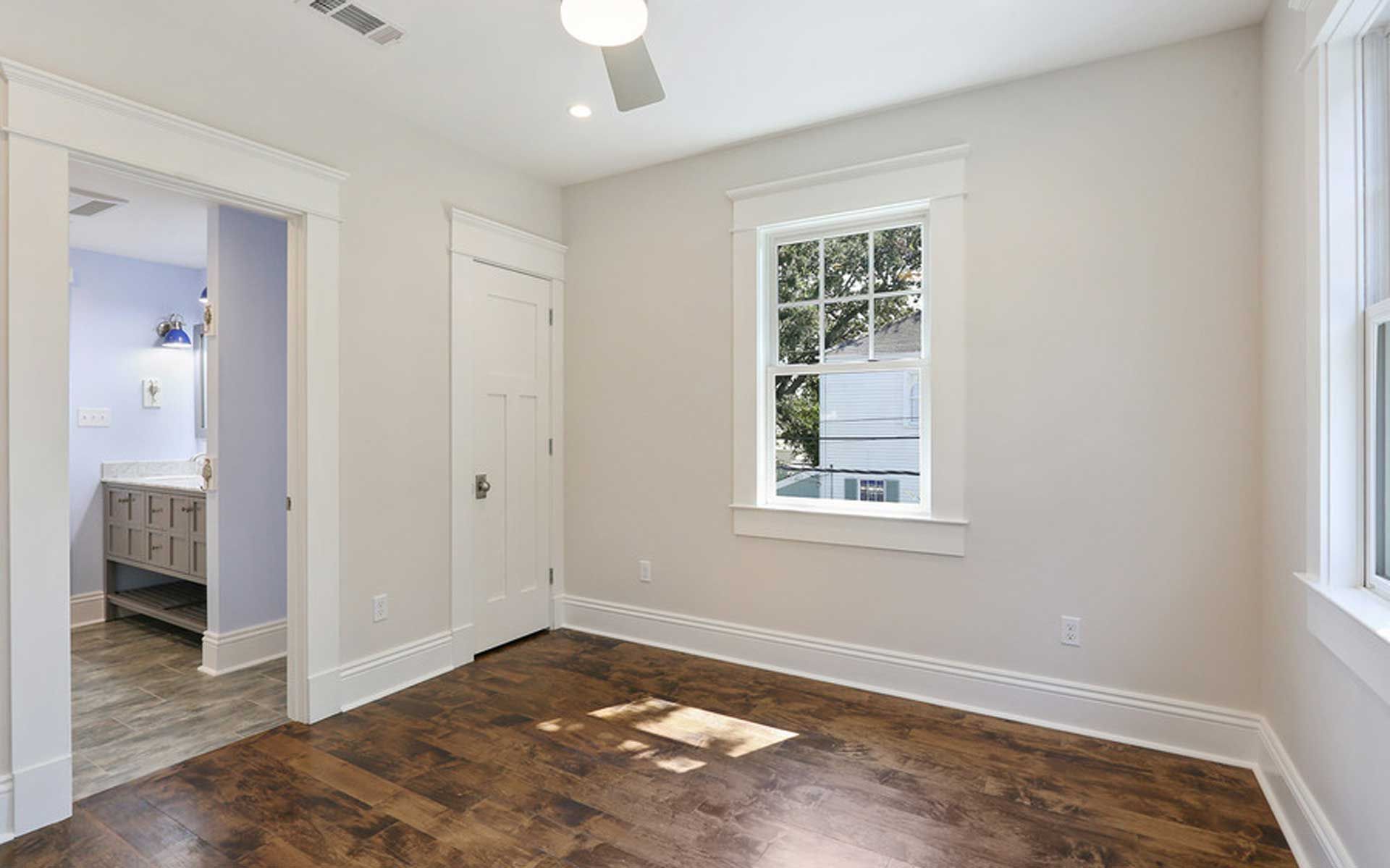 An empty bedroom with hardwood floors and a ceiling fan.