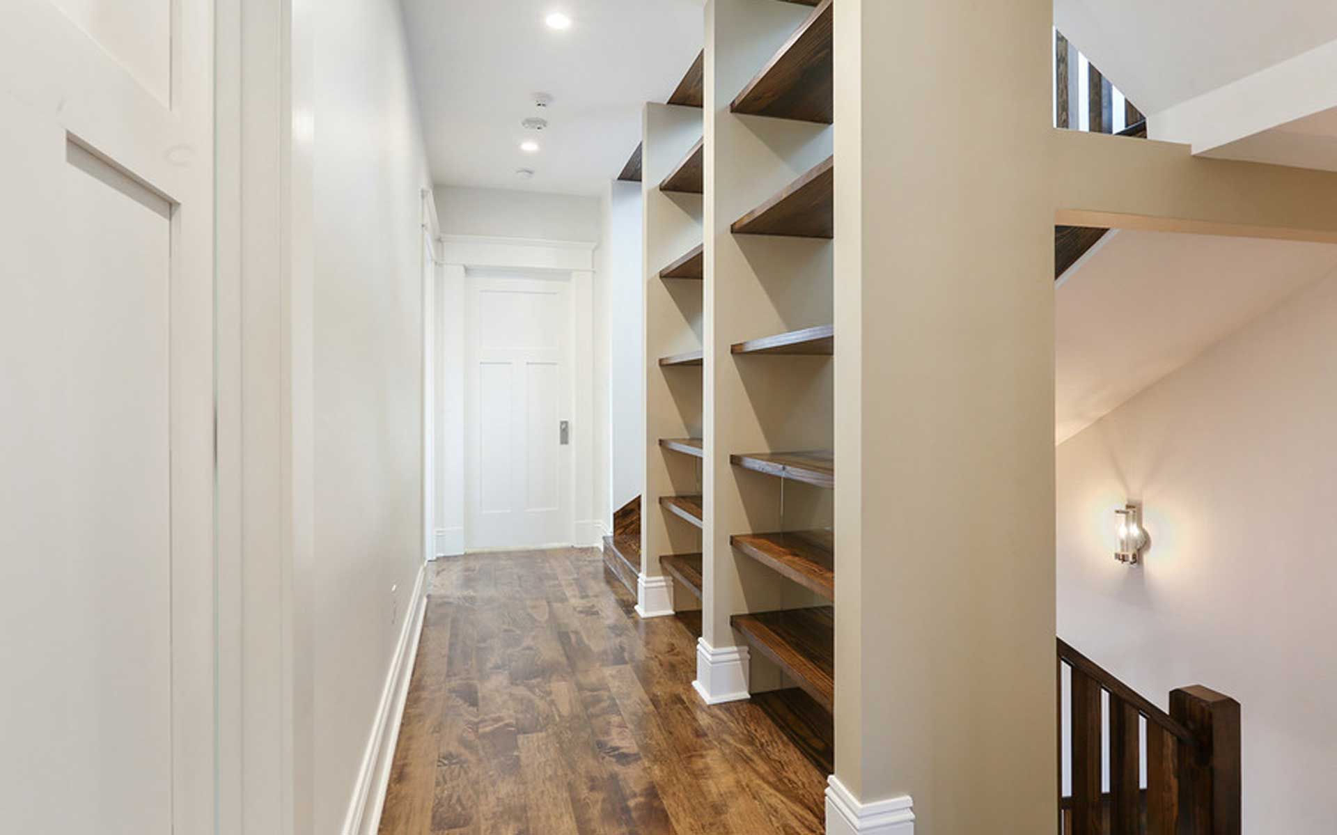 A hallway with wooden floors and shelves in a house.