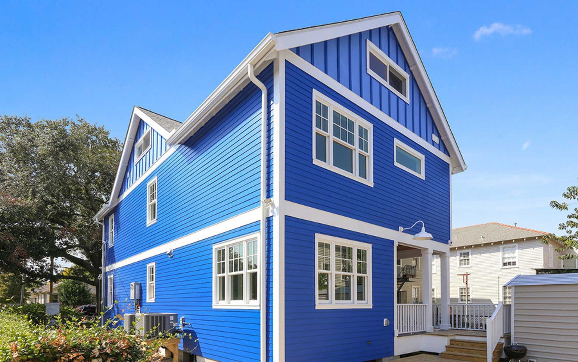 A blue house with white trim and windows on a sunny day.