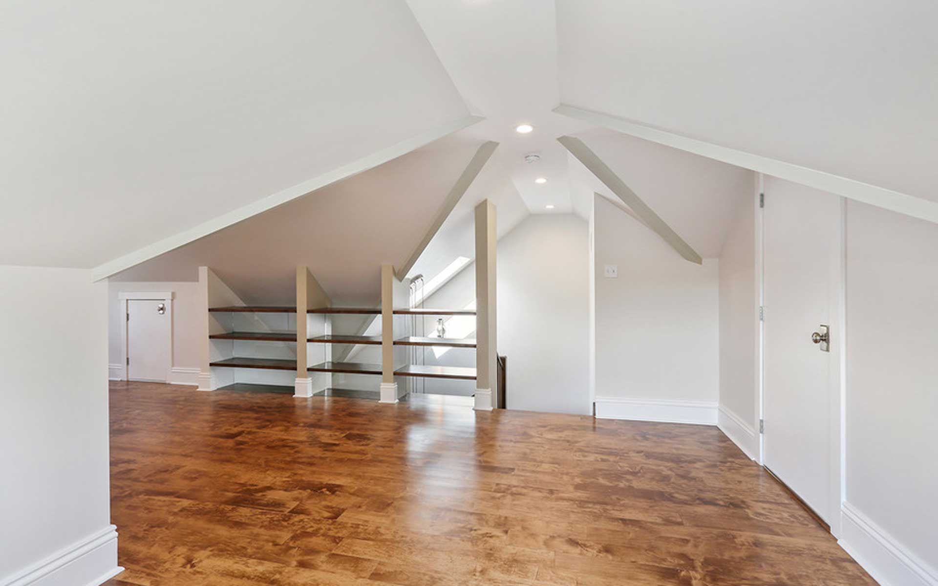 An empty room with a wooden floor and white walls