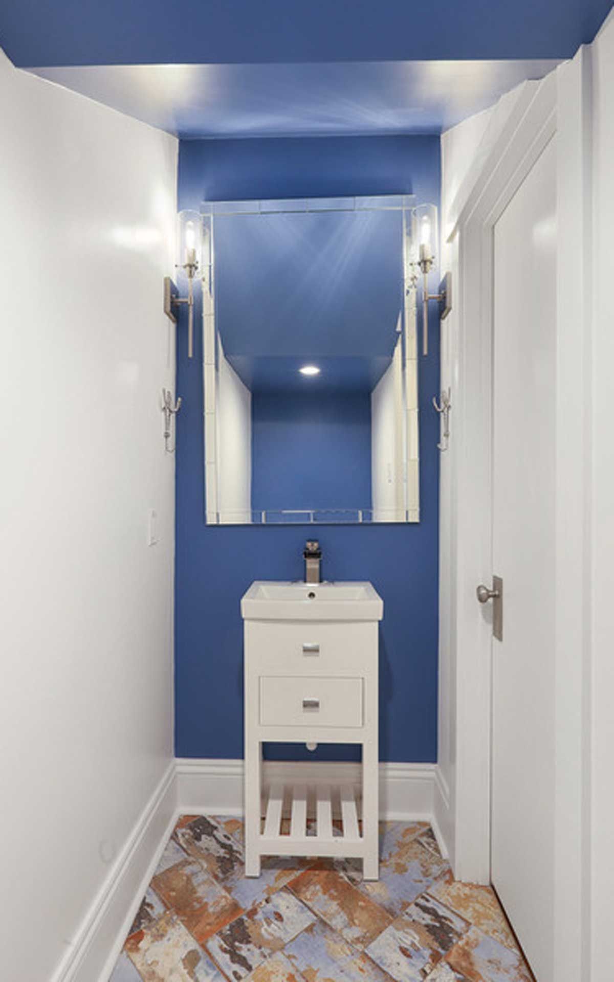 A bathroom with a sink , mirror and blue walls.