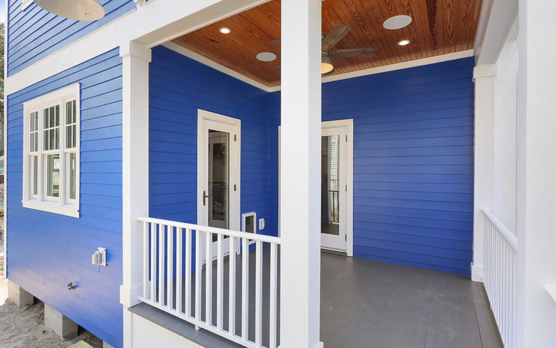 A blue and white house with a porch and a ceiling fan.