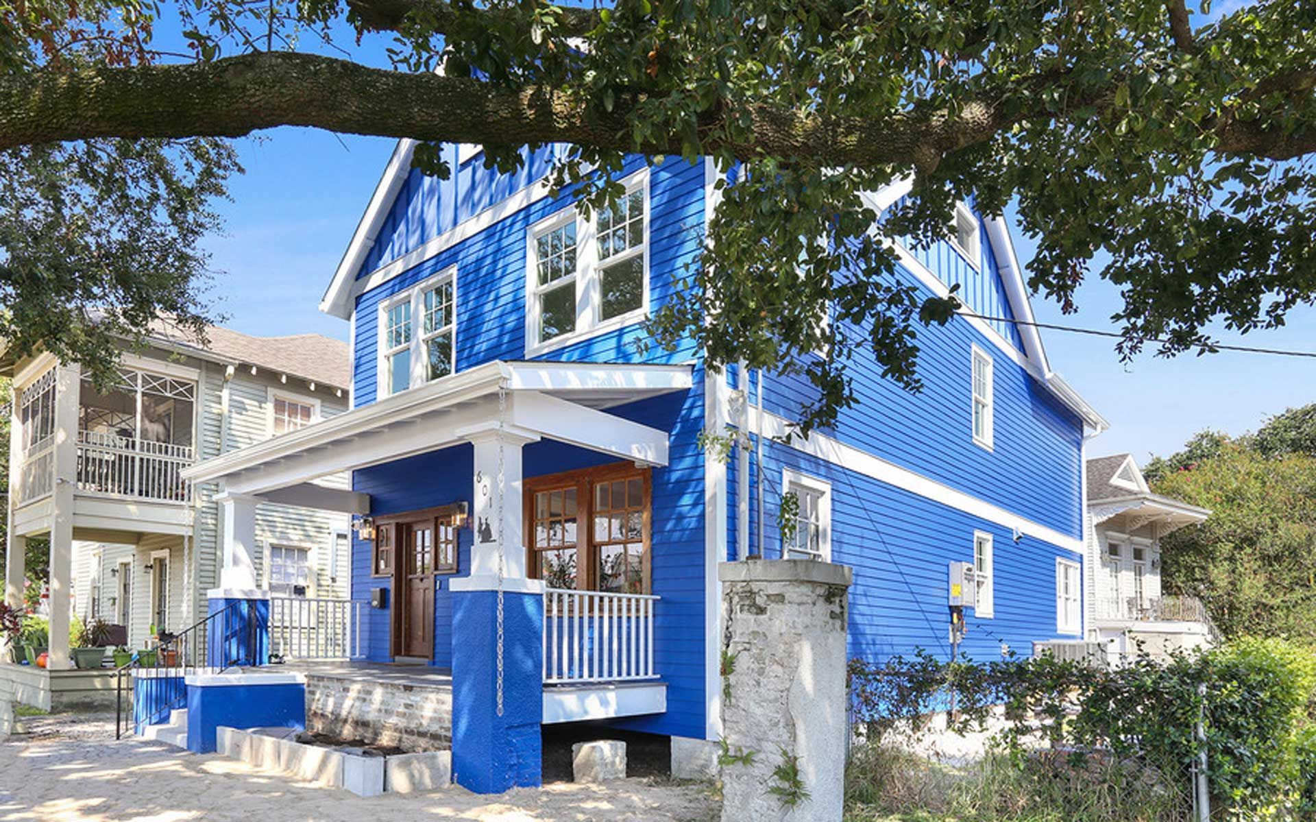 A blue and white house with a tree in front of it