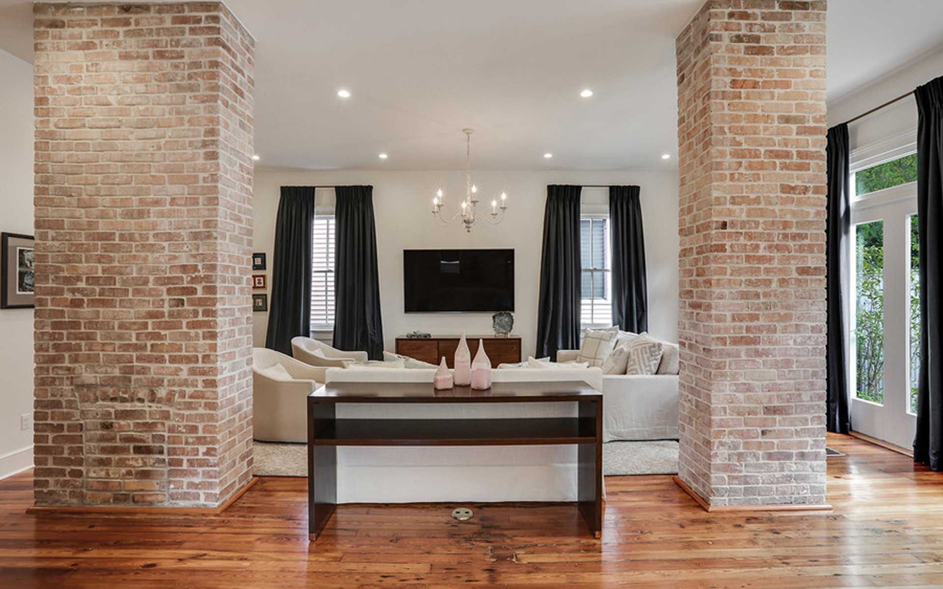 A living room with brick columns , a couch , a table and a television.