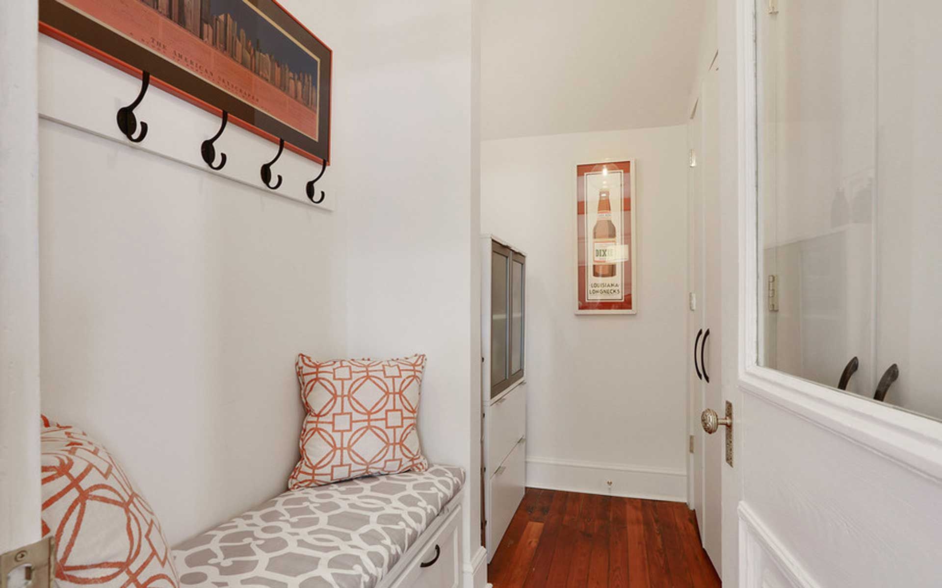 A hallway with a bench and hooks on the wall.