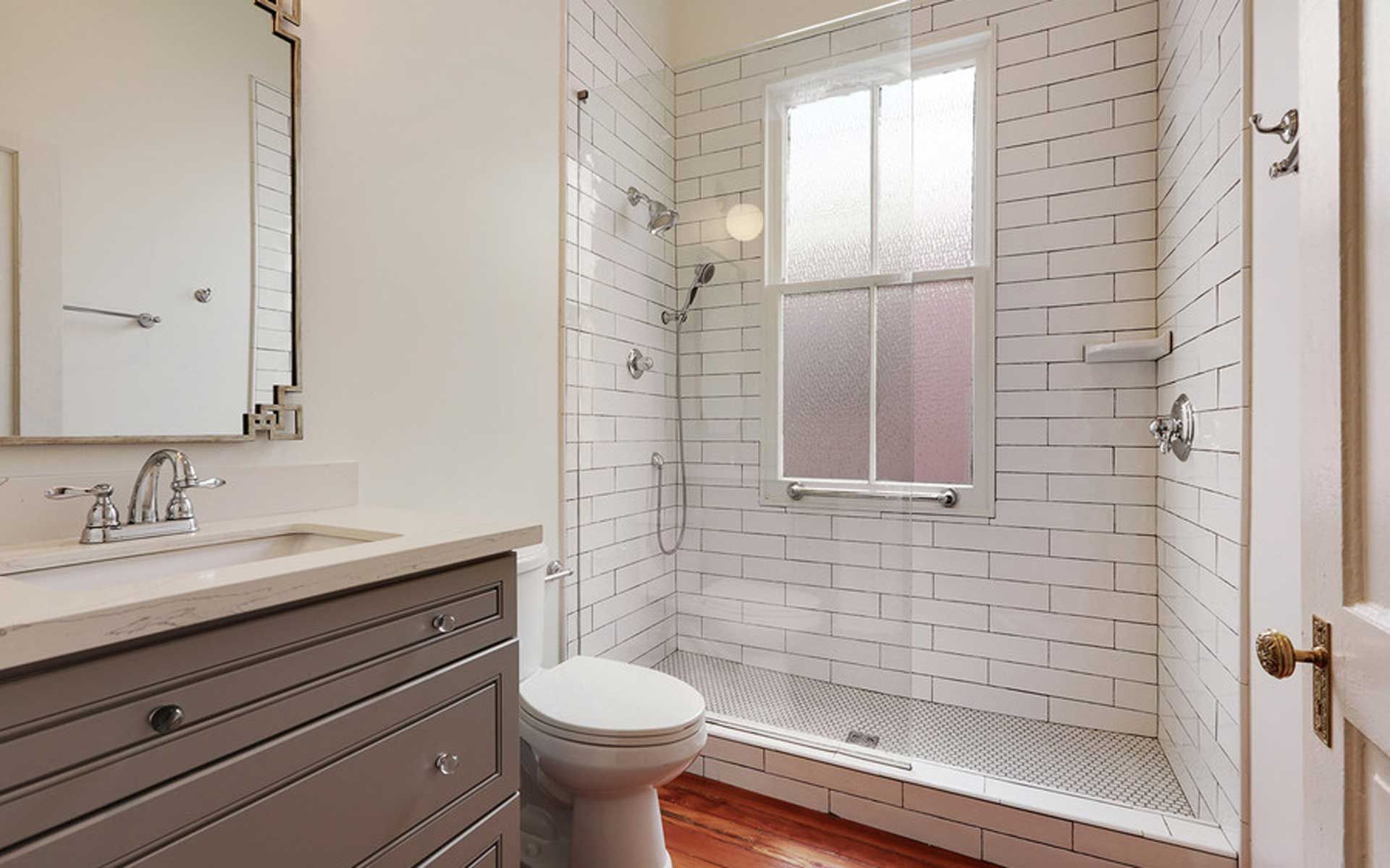 A bathroom with a toilet , sink , mirror and walk in shower.