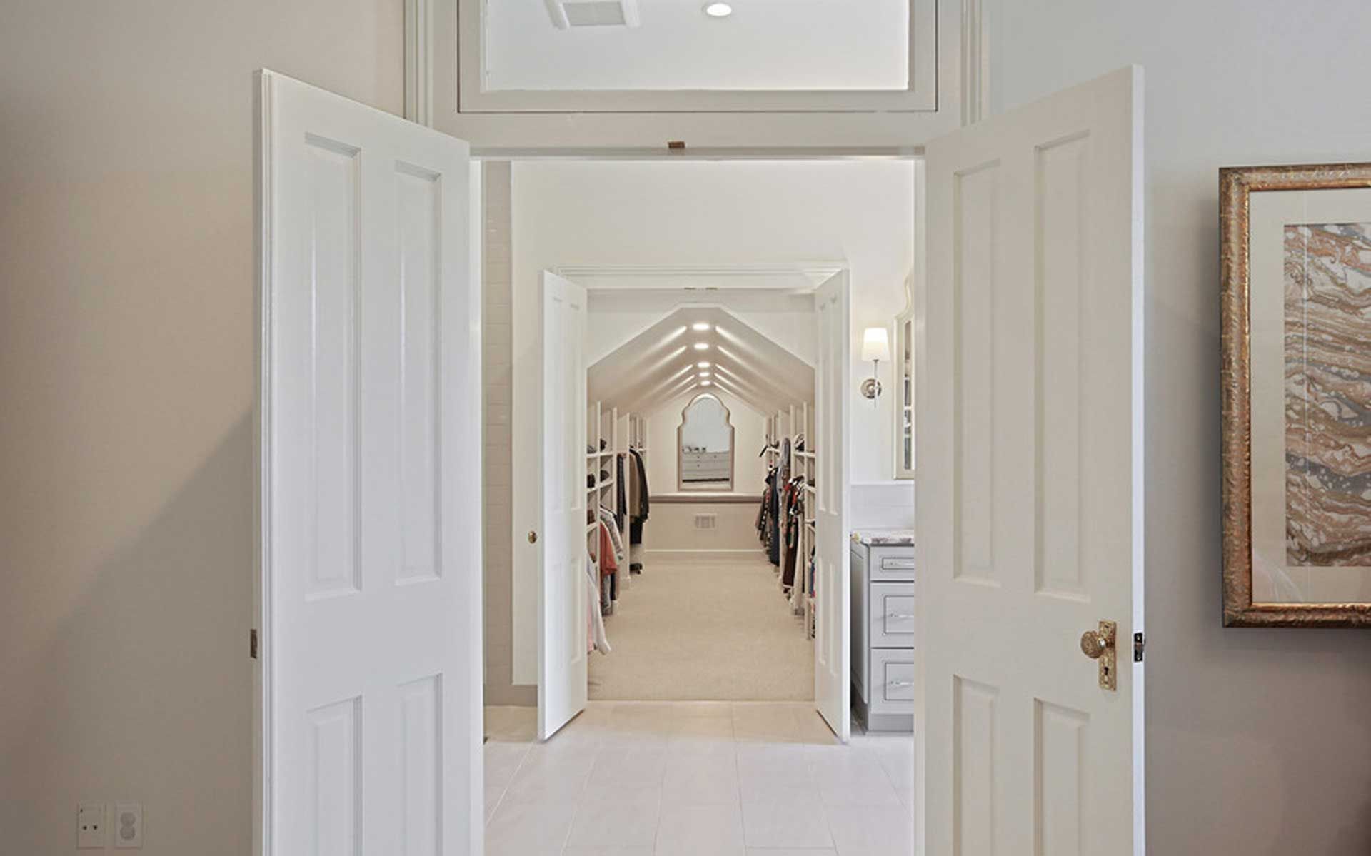 A hallway in a house with white doors and a picture on the wall.