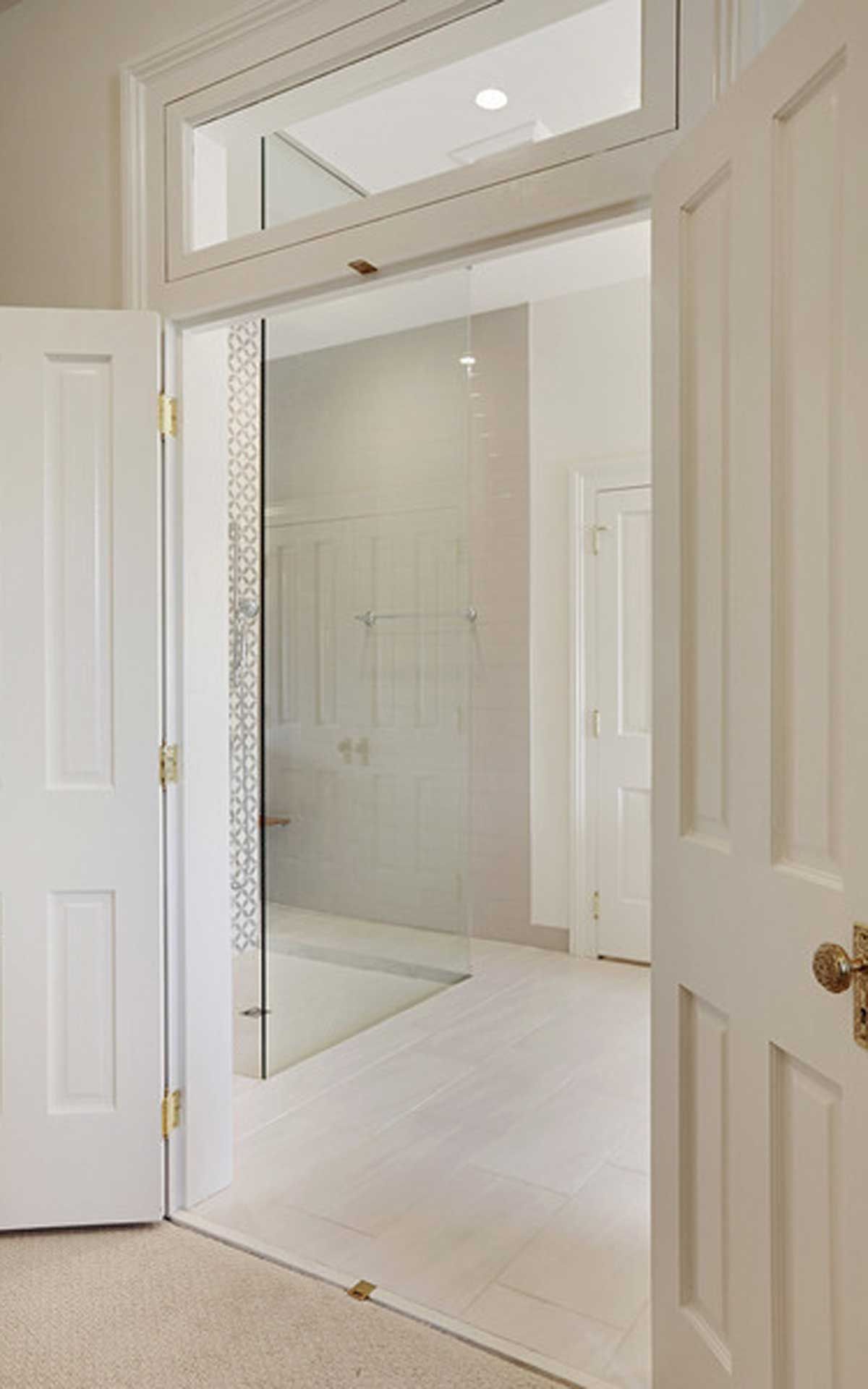 A white door is open to a bathroom with a glass shower door.