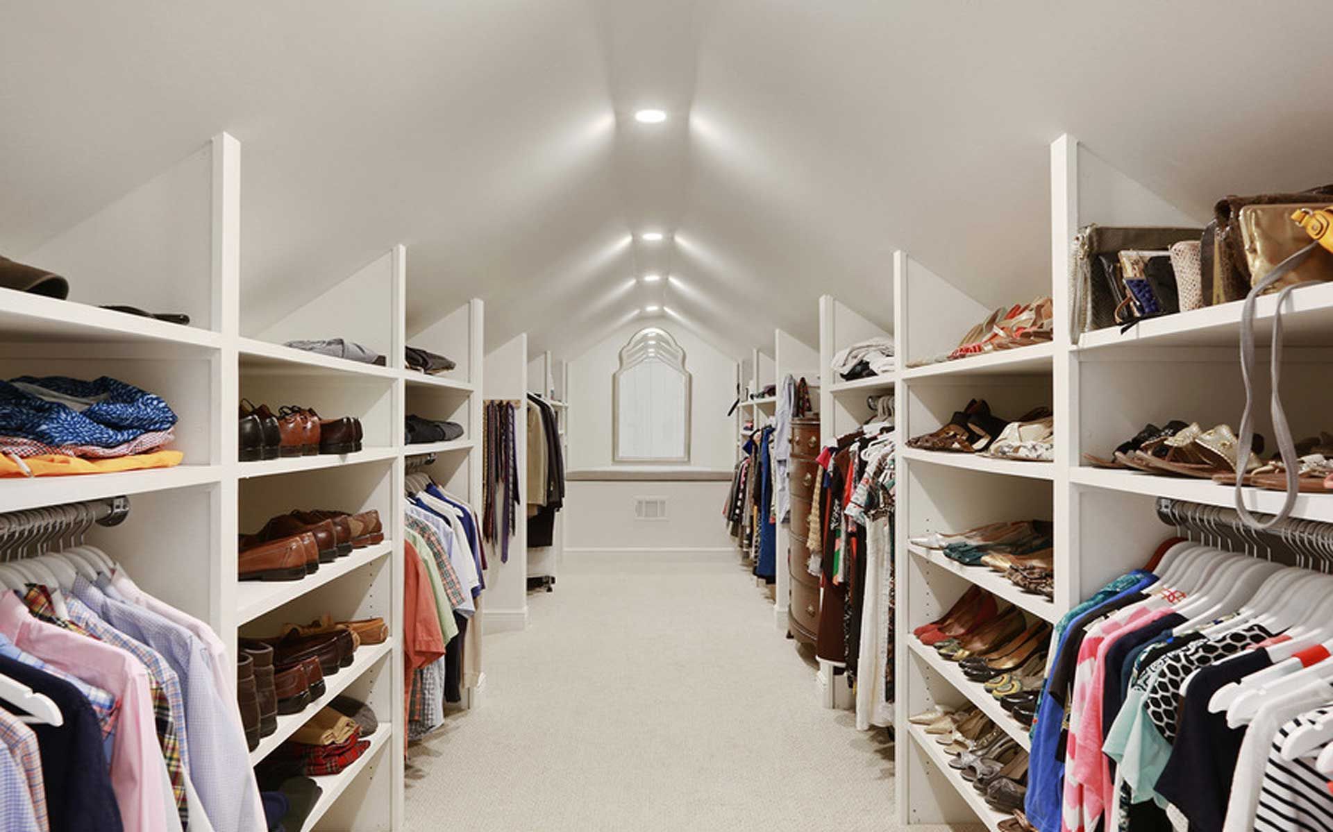 A large walk in closet filled with clothes and shoes.