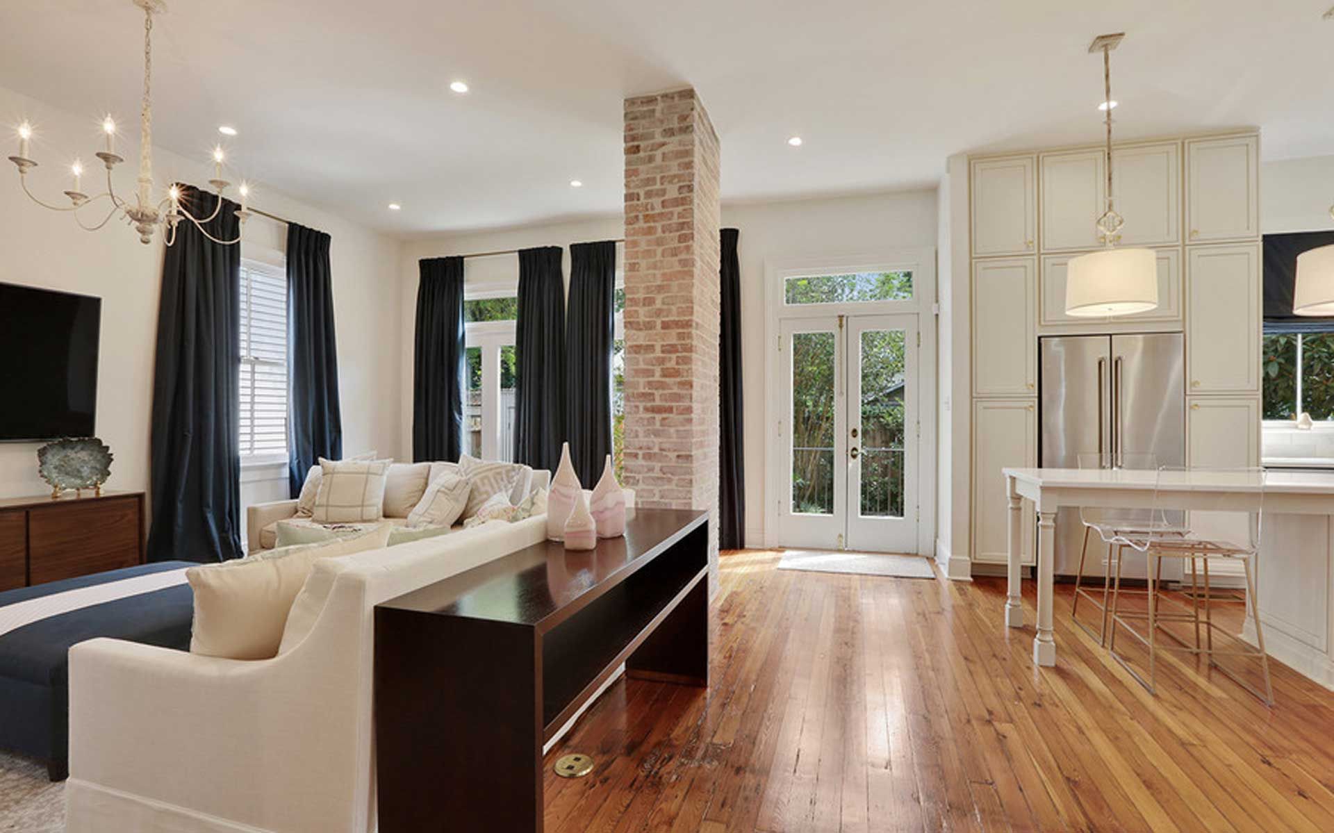 A living room with hardwood floors , a couch , a table and a television.