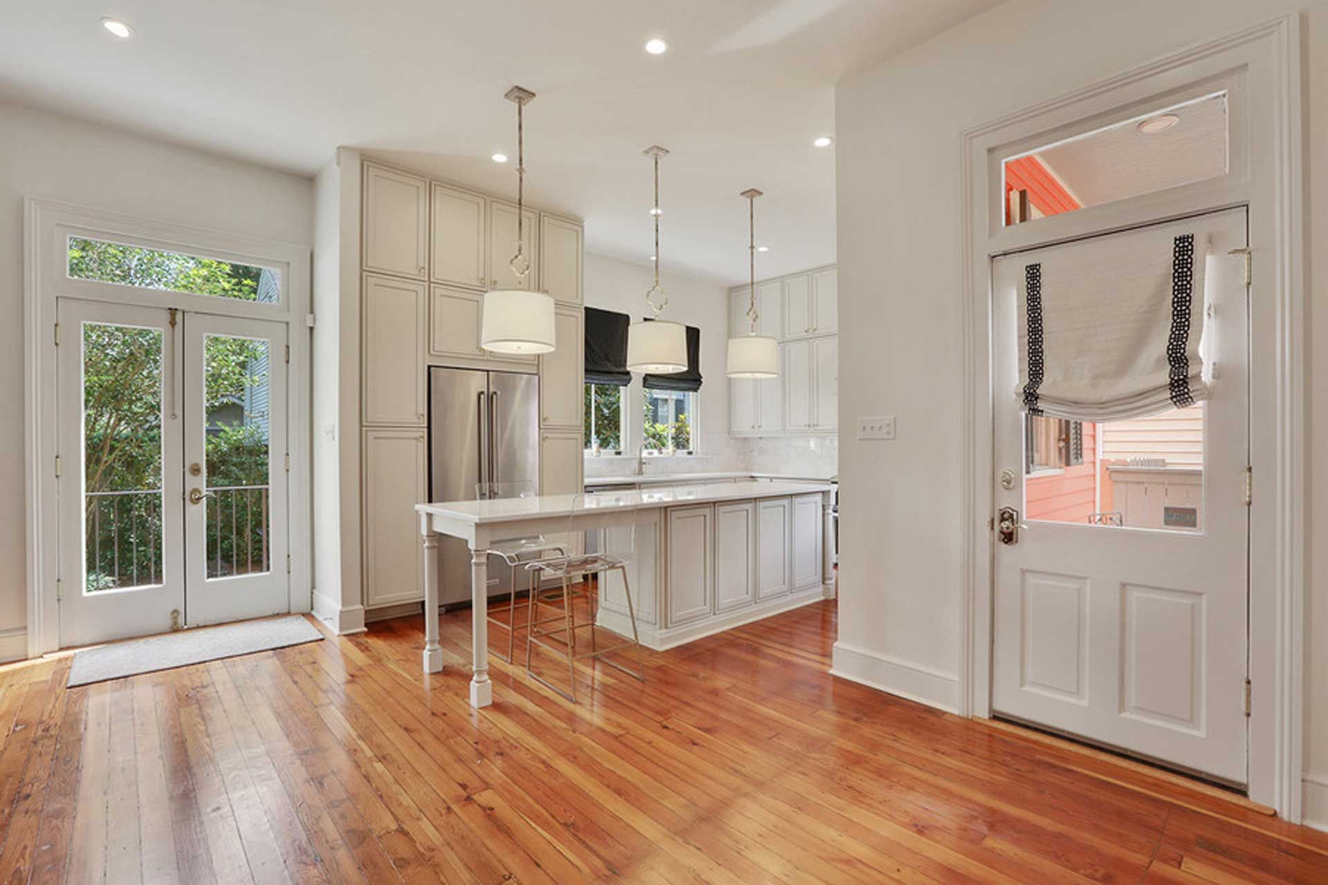 An empty kitchen with hardwood floors and white cabinets.