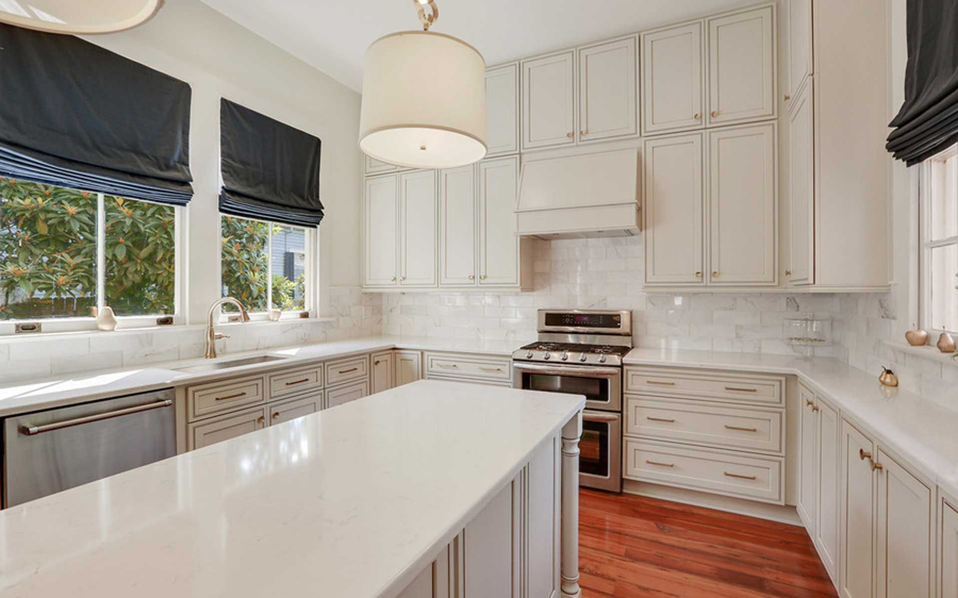 A kitchen with white cabinets , stainless steel appliances , and a large island.