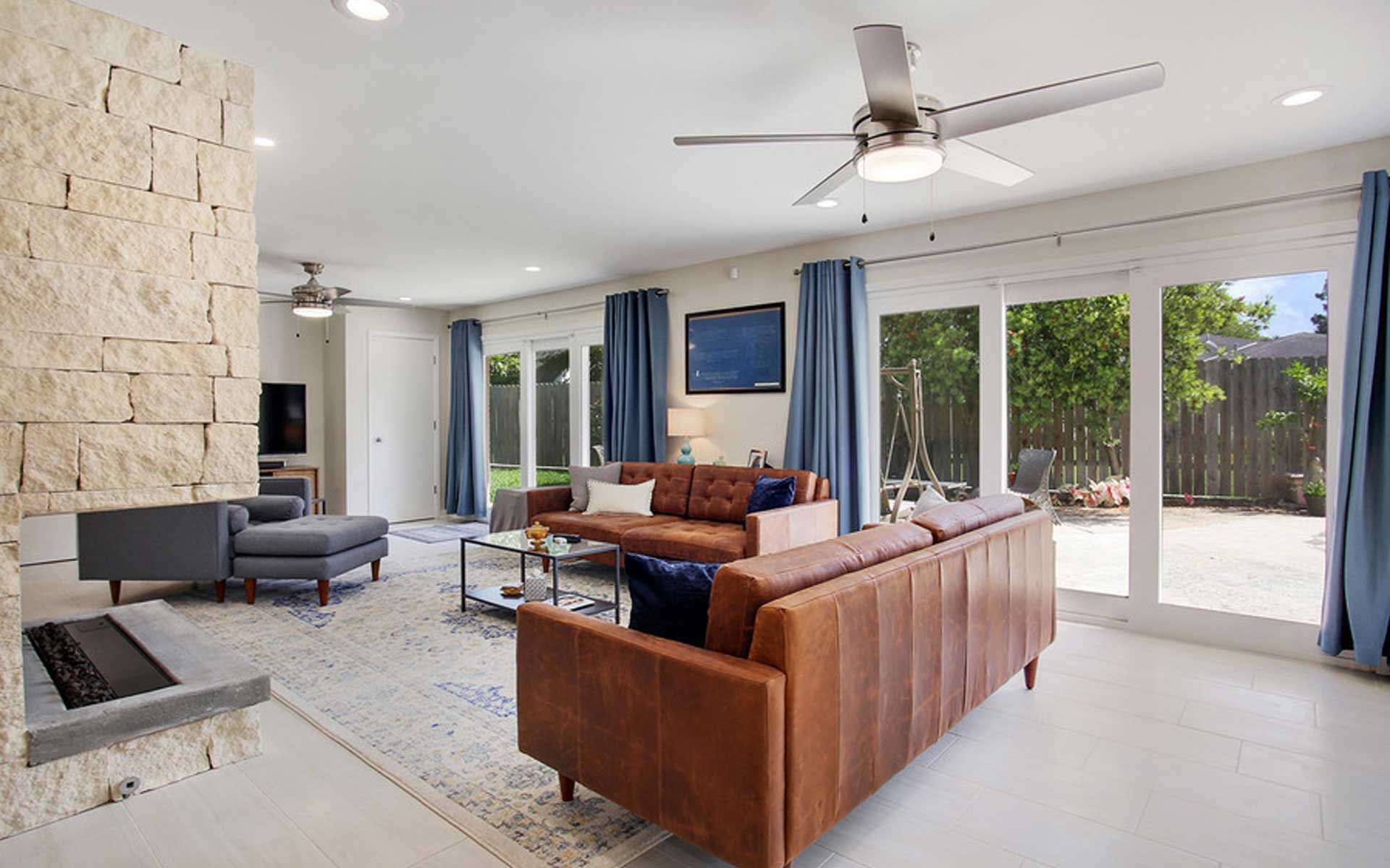 A living room with a brown couch and a ceiling fan.