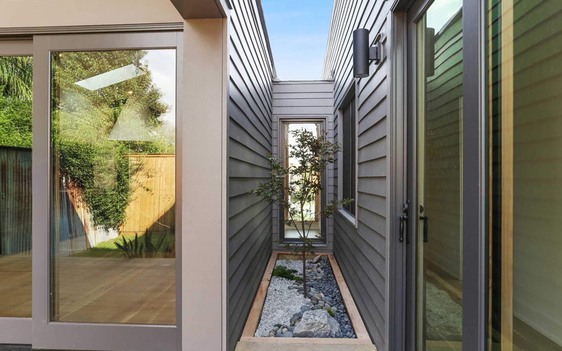 A narrow hallway between two houses with sliding glass doors