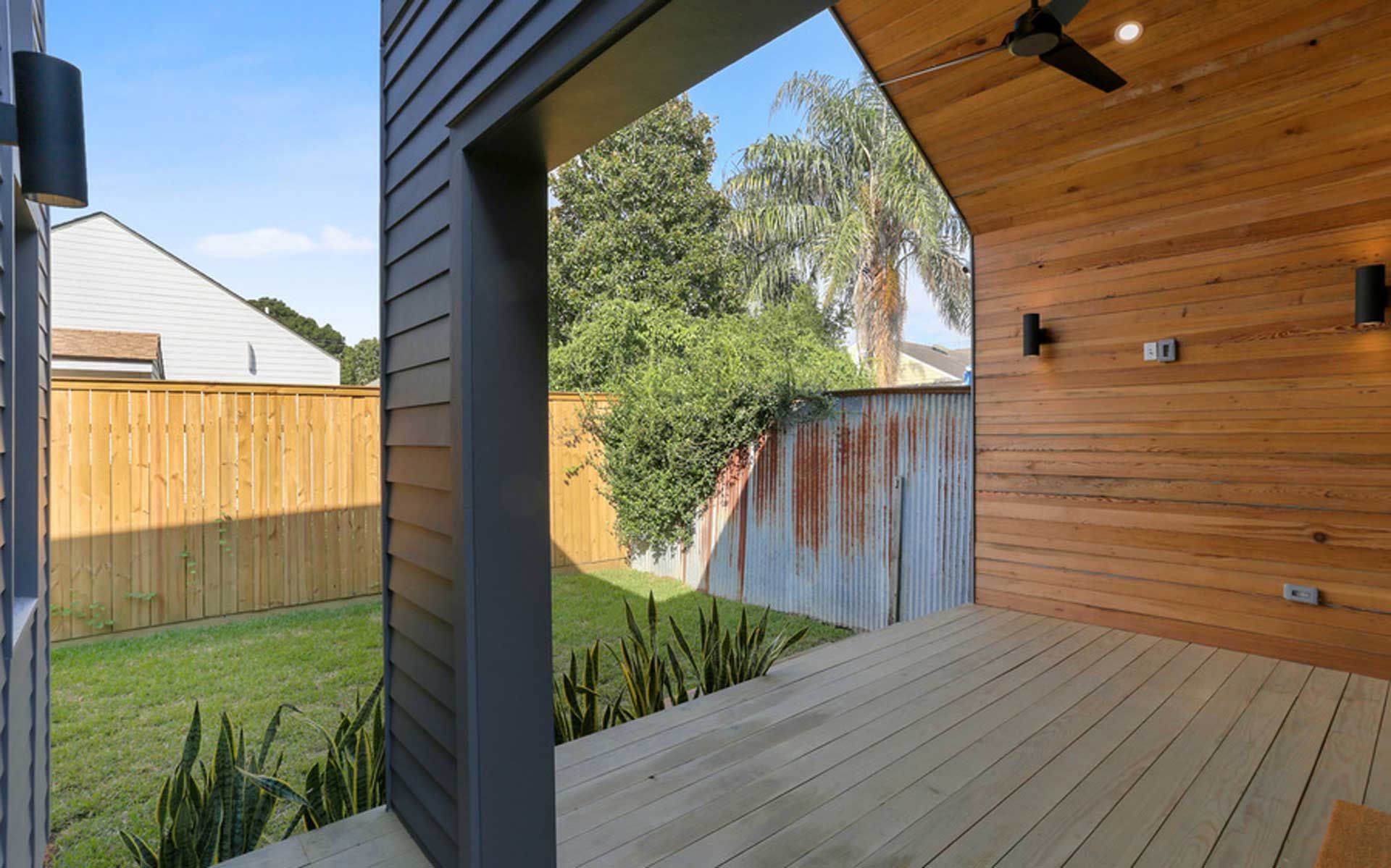 A patio with a wooden deck and a ceiling fan