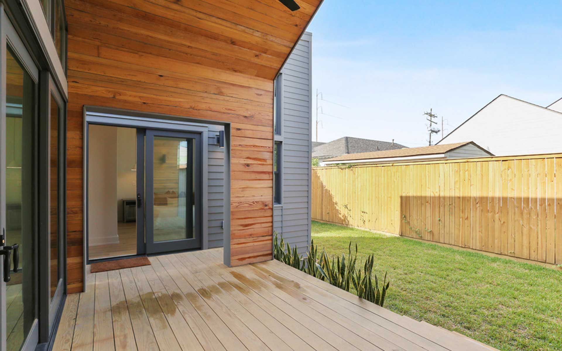 A house with a wooden deck and a fence in the backyard.