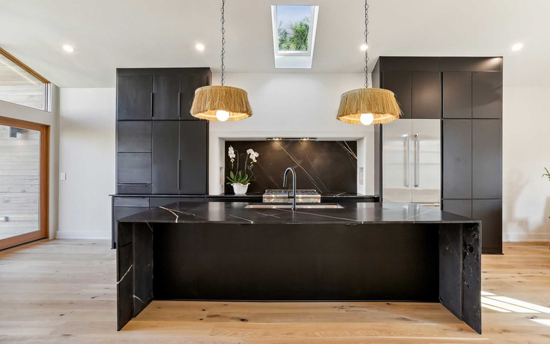 A kitchen with black cabinets and a large island in the middle.