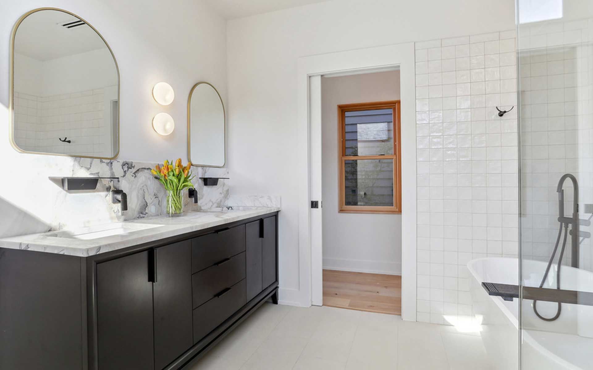 A bathroom with two sinks , a tub , and two mirrors.