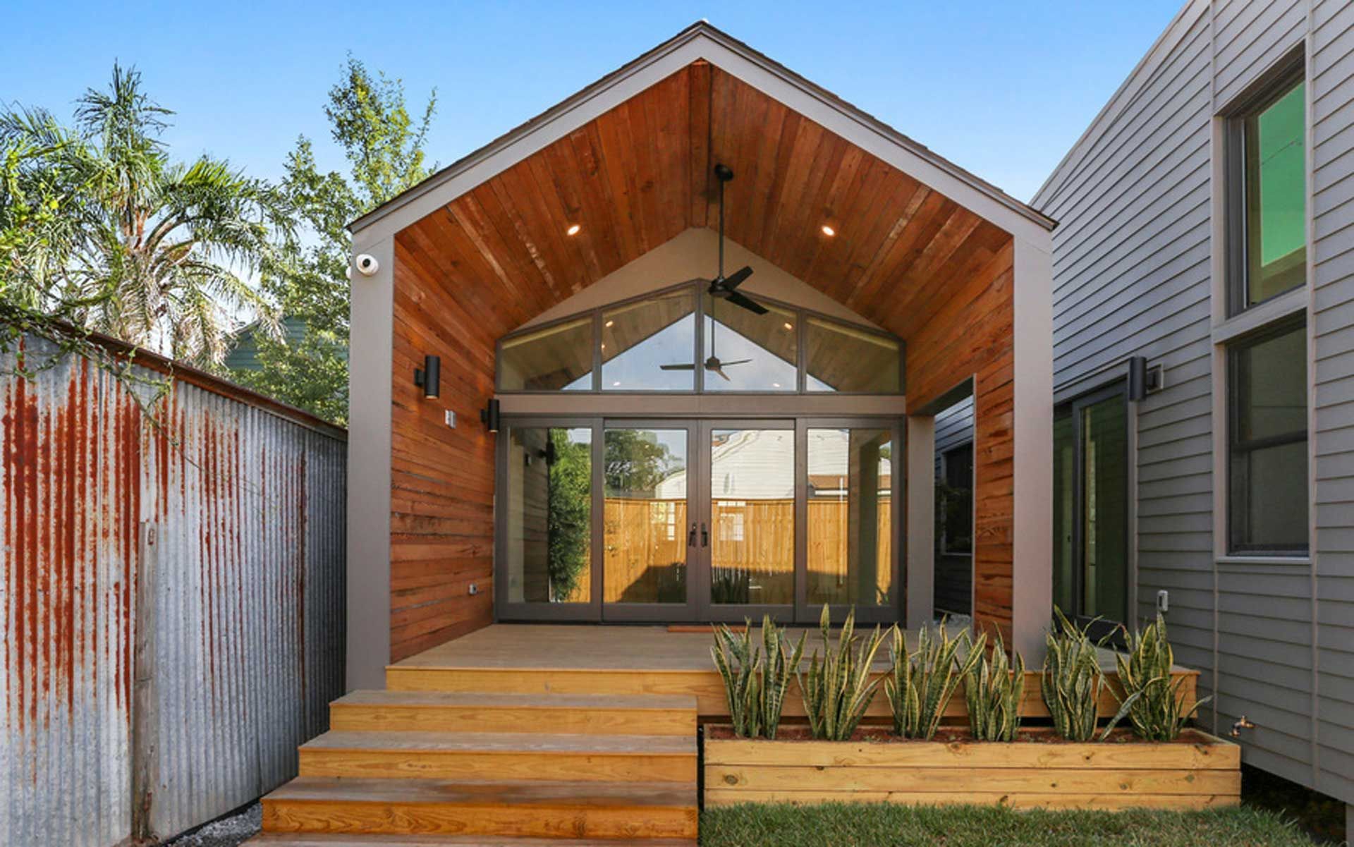 The back of a house with a wooden roof and sliding glass doors.