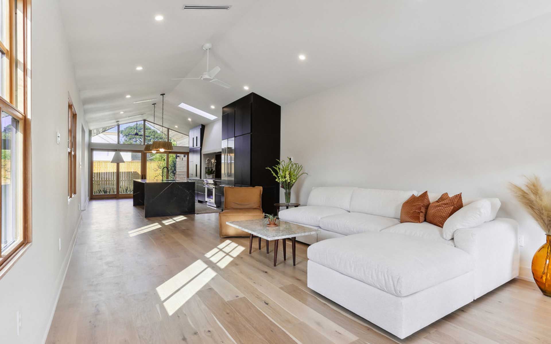 A living room with a white sectional couch and wooden floors.