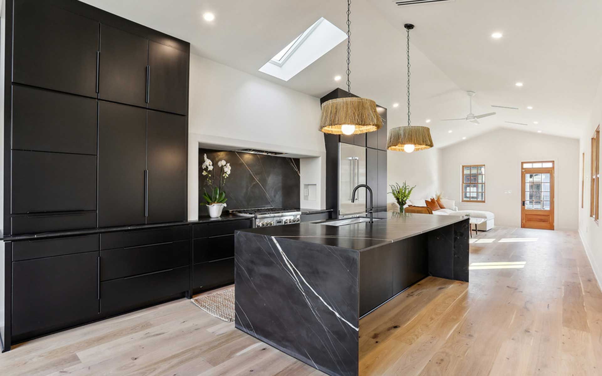 A kitchen with black cabinets and a large island in the middle.