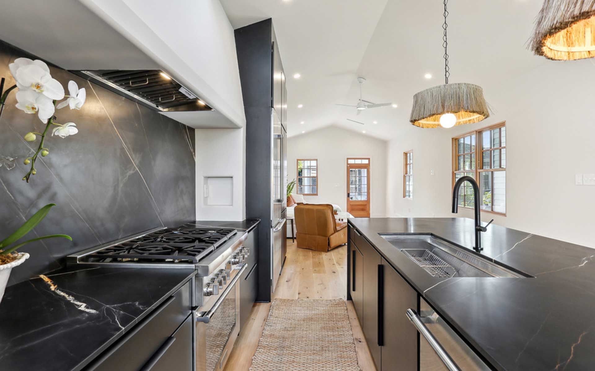 A kitchen with black counter tops and a stove top oven.