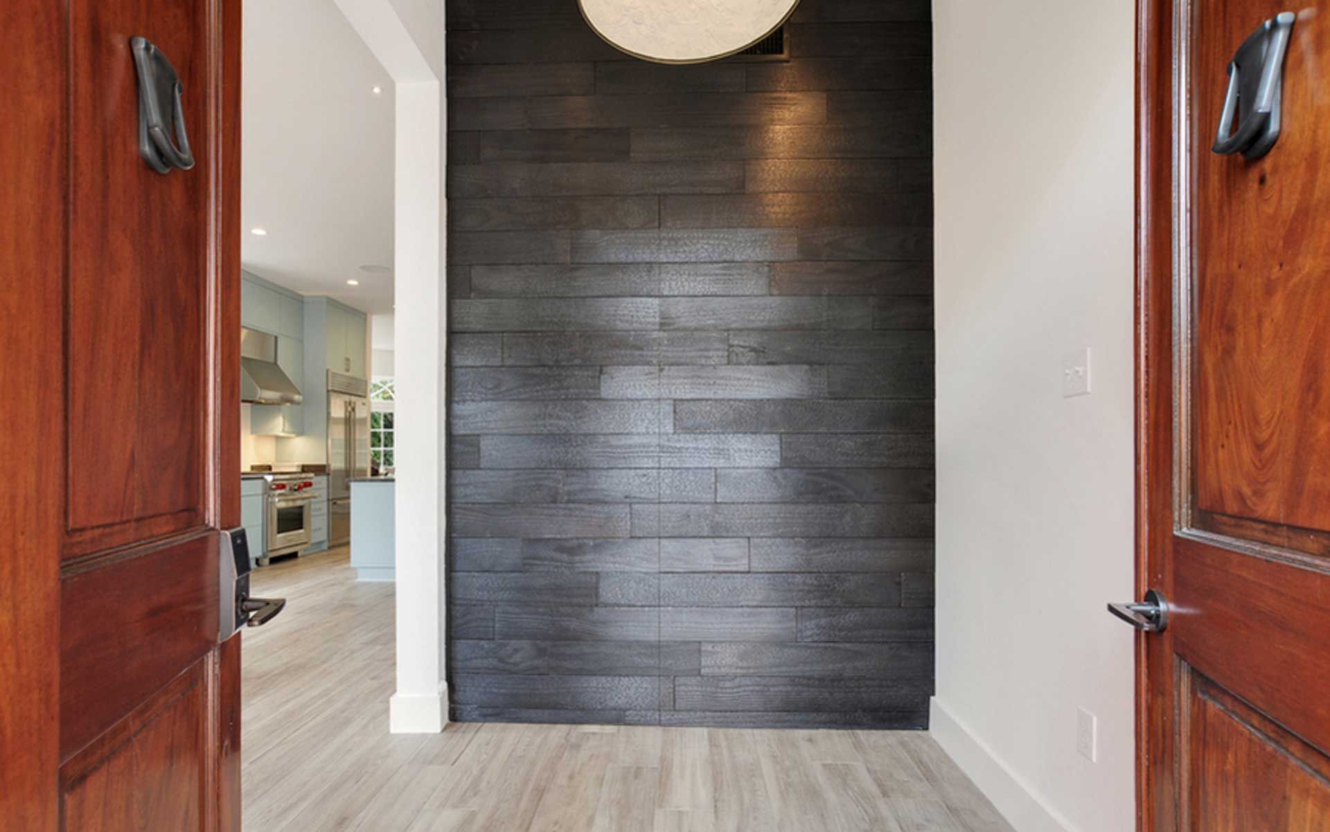 A hallway with a wooden door and a black wall.