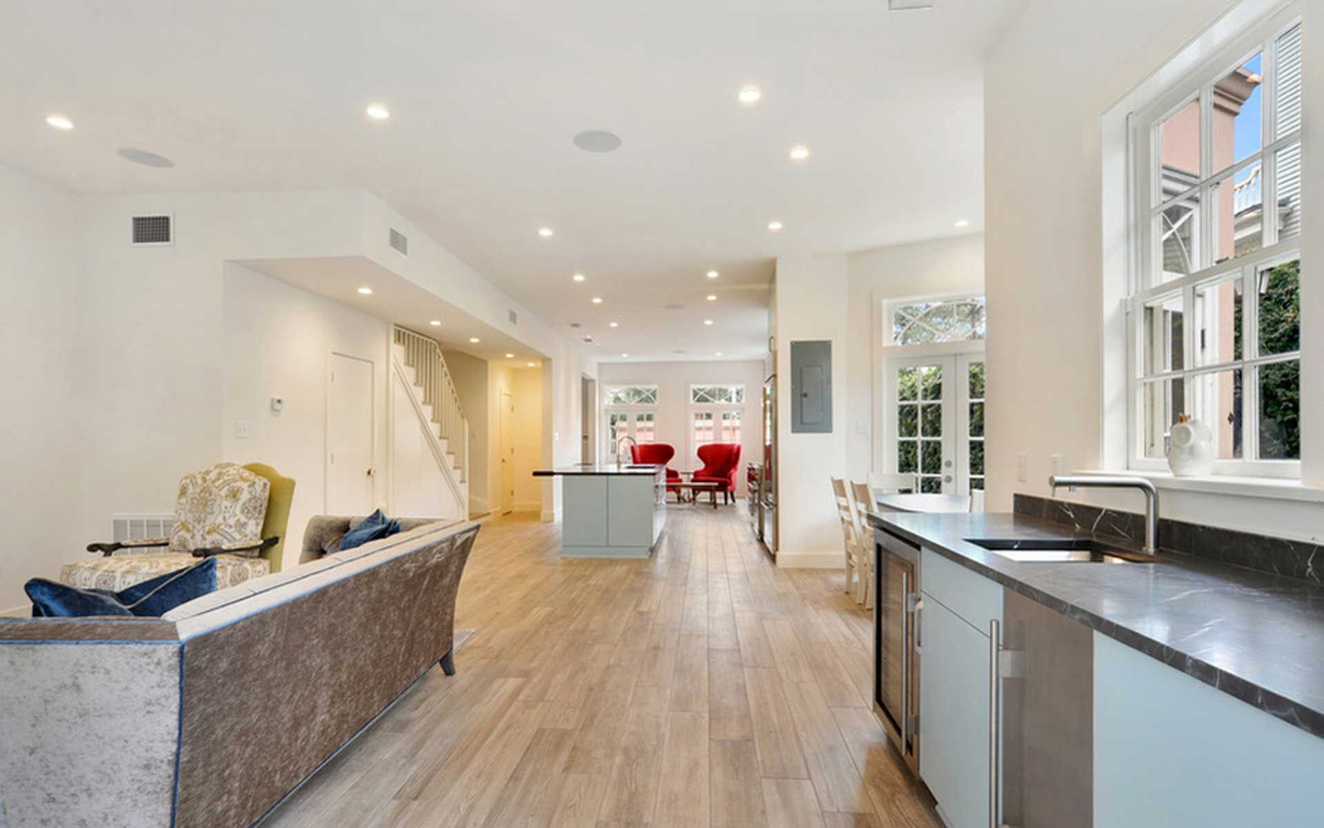 A living room with a couch , chairs , and a kitchen with a sink.