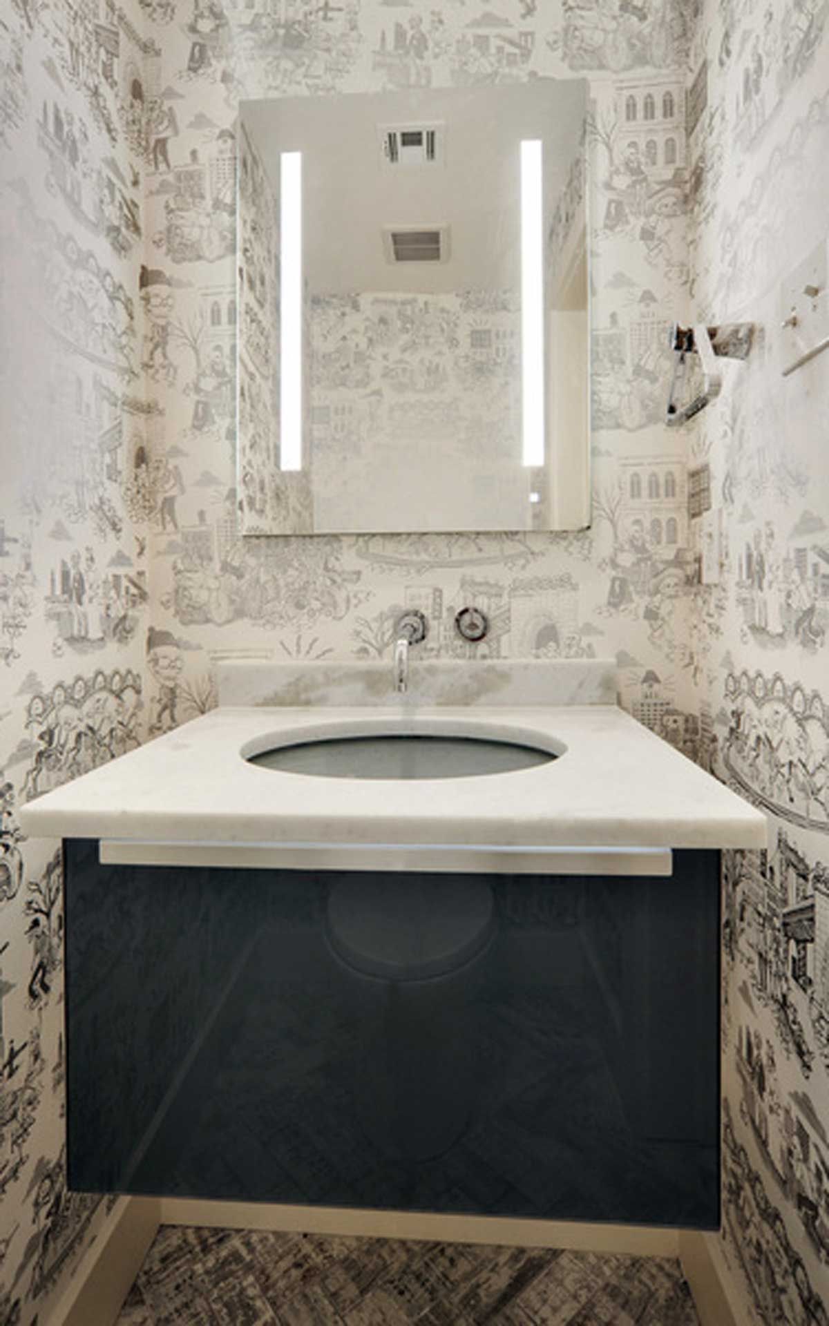A bathroom with a sink , mirror and wallpaper.