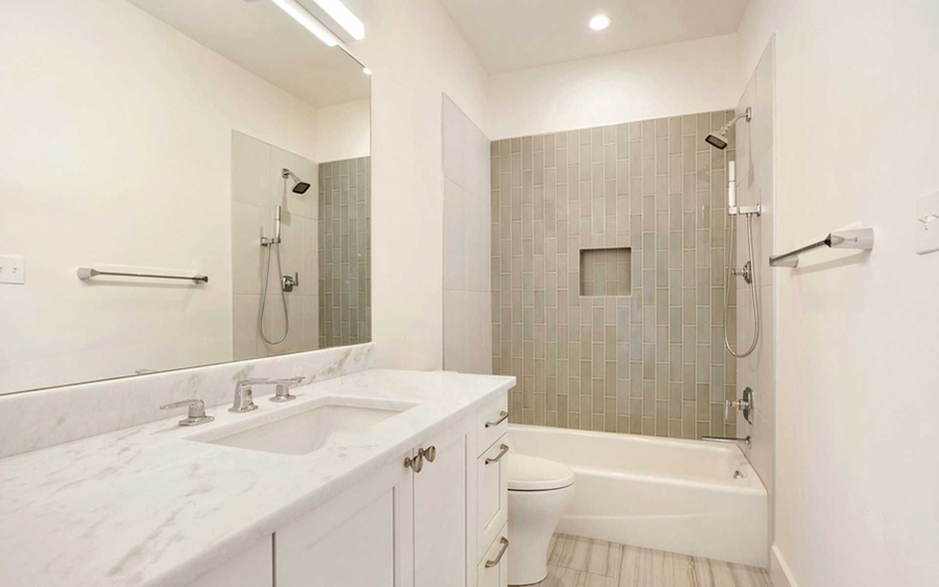 A bathroom with a sink , toilet , shower and mirror.