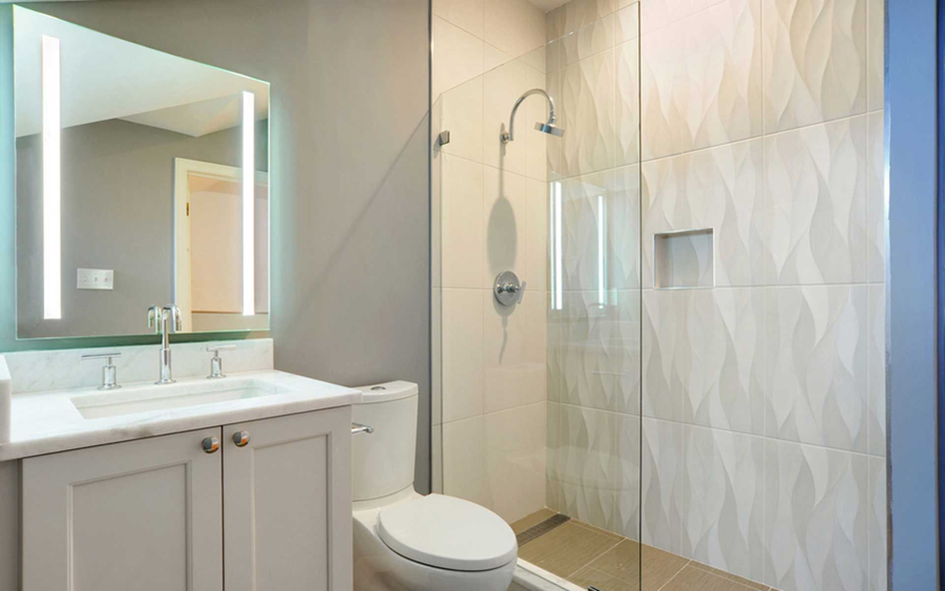 A bathroom with a toilet , sink , mirror and walk in shower.