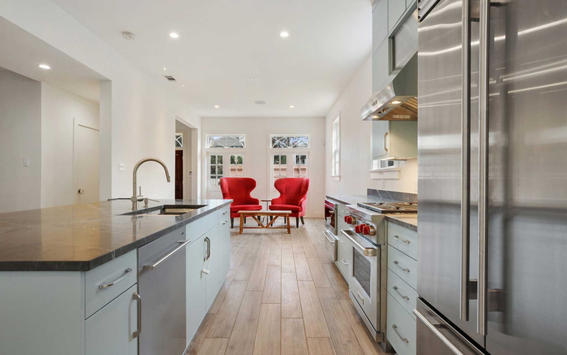 A kitchen with stainless steel appliances and a living room in the background.