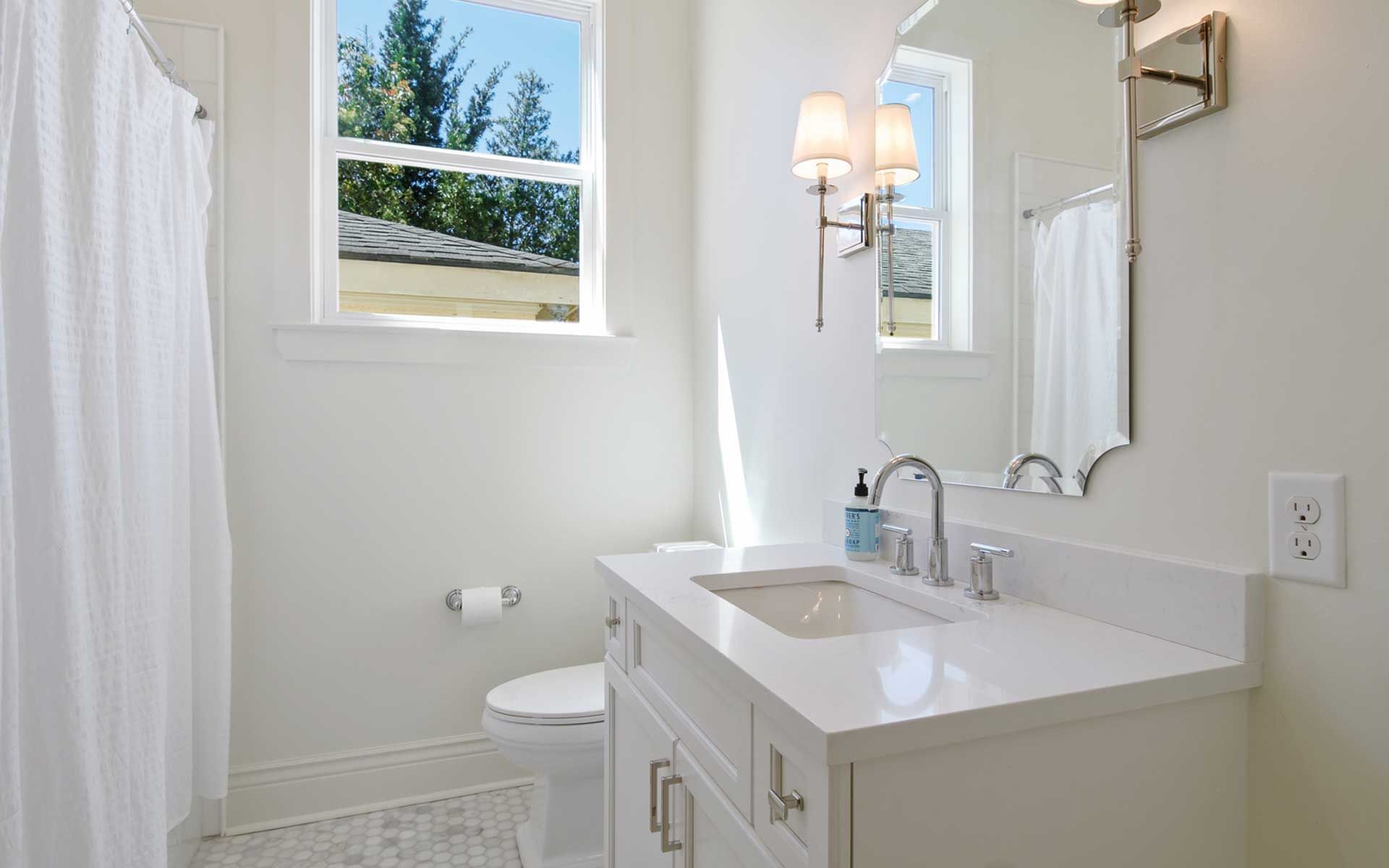 A bathroom with a sink , toilet , mirror and shower curtain.