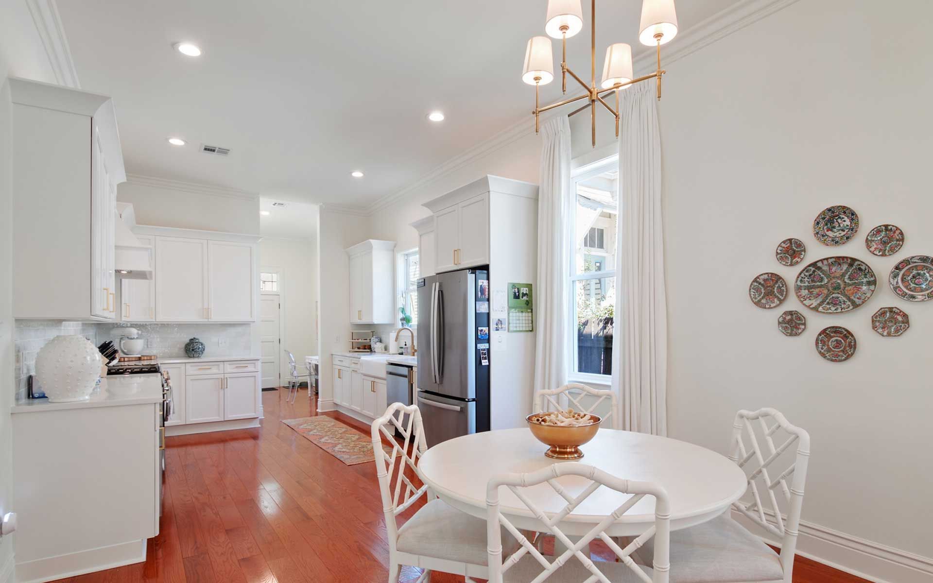 A dining room with a round table and chairs and a kitchen in the background.
