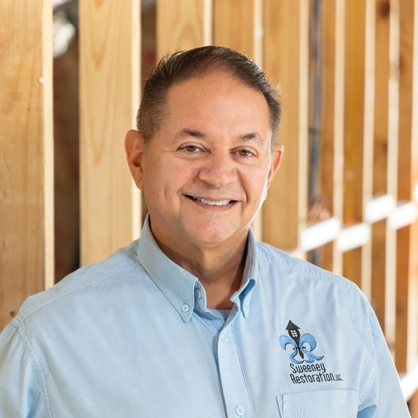 A man wearing a hard hat and goggles is standing in a room.