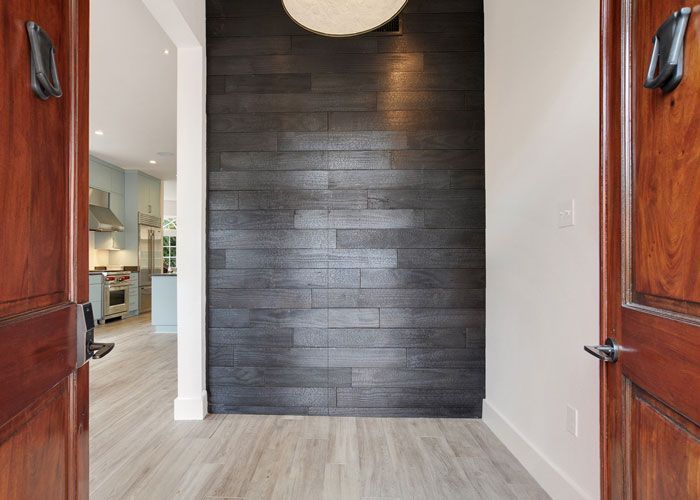 A hallway with a wooden floor and a black wall.