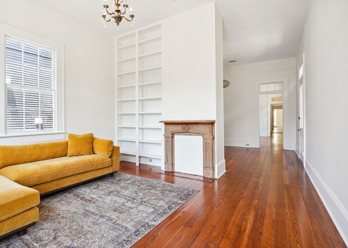 A living room with a yellow couch and a fireplace.
