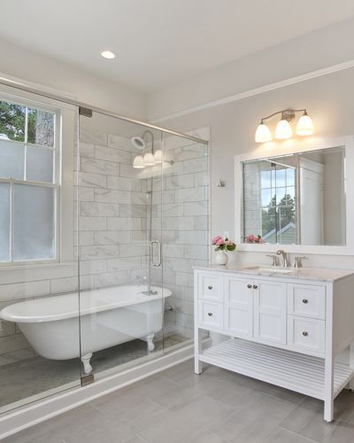 A bathroom with a tub , sink , mirror and shower.