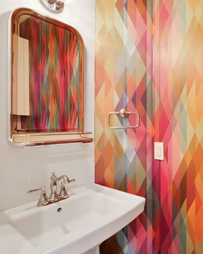 A bathroom with a sink , mirror and colorful wallpaper.