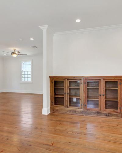 An empty living room with hardwood floors and a ceiling fan.