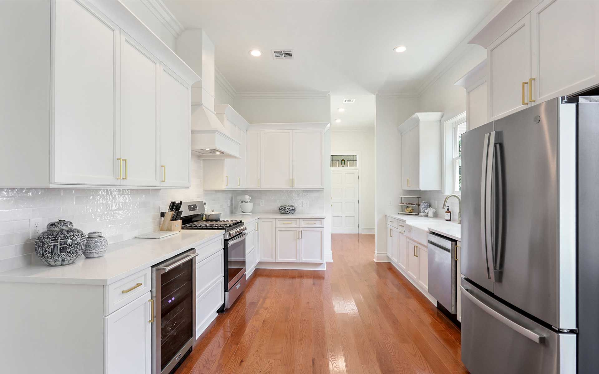 A kitchen with white cabinets , stainless steel appliances , and hardwood floors.