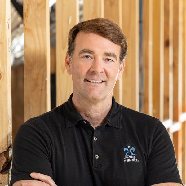 A young man is holding a straw hat in his hand and smiling.