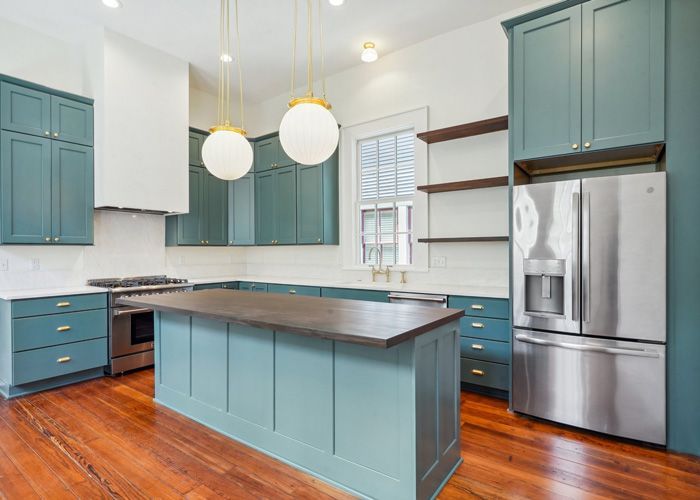 A kitchen with blue cabinets , stainless steel appliances , and a large island.
