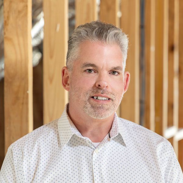 A man in a green jacket is looking at the camera.