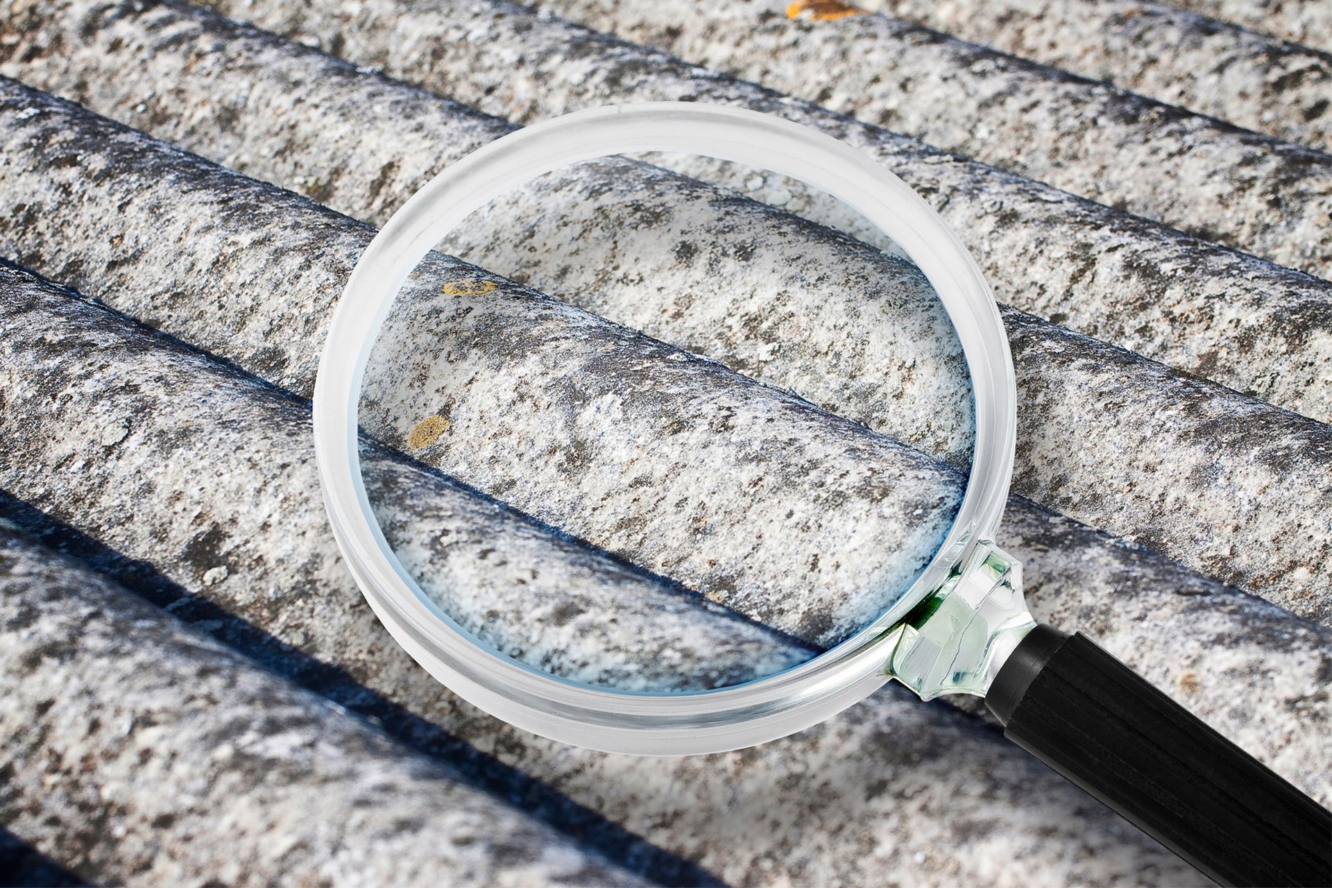 Magnifying glass over a weathered gray asbestos roof.