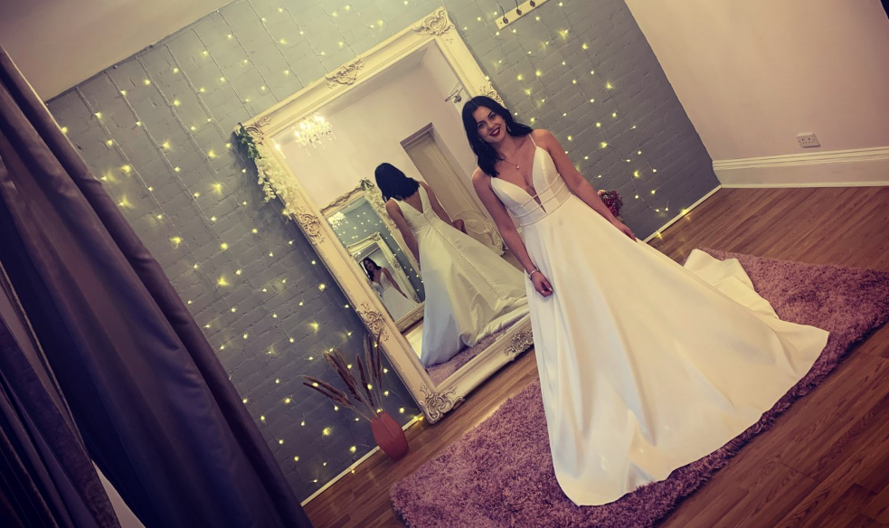 girl in wedding dress in front of mirror and fairy lights
