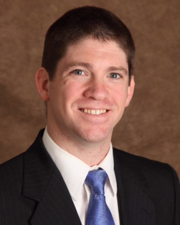 A man in a suit and tie smiles for the camera